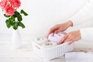 women s hands neatly fold towels into basket